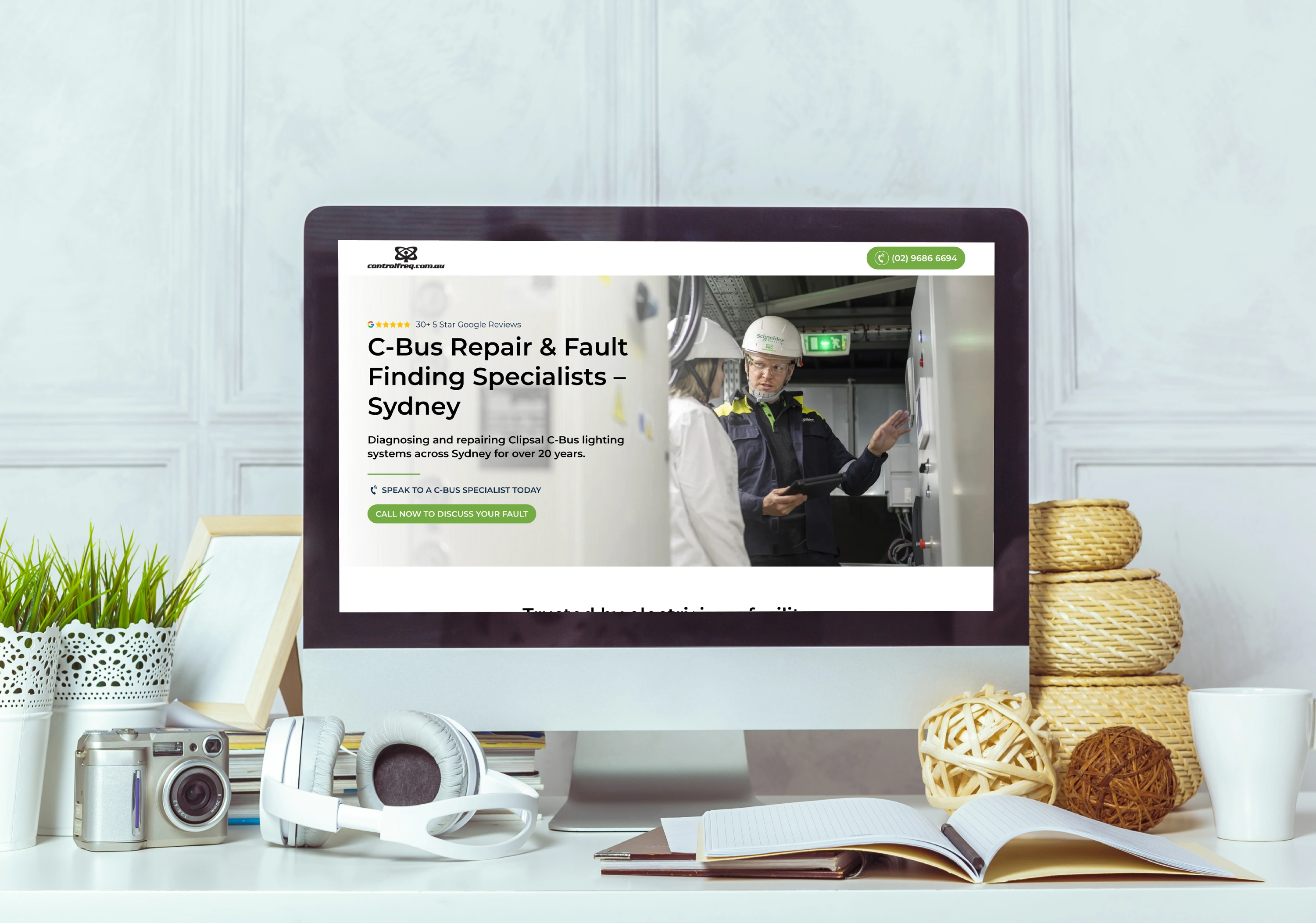 Desktop monitor displaying a C-Bus repair and fault-finding Sydney webpage with a technician image and green call-to-action buttons.