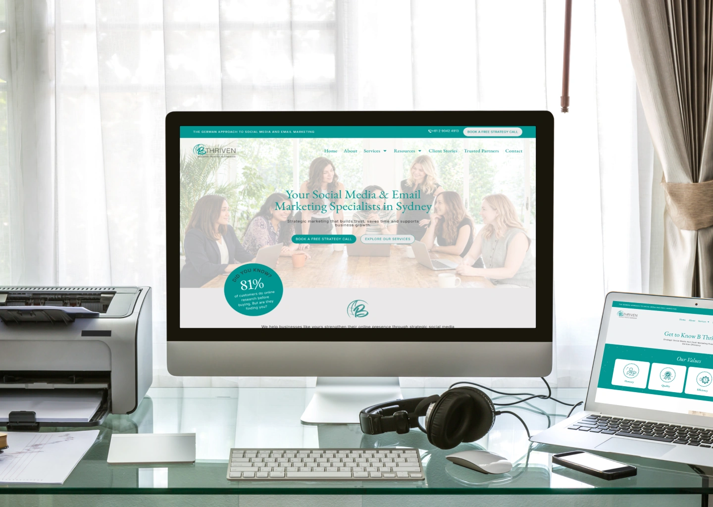 Desktop computer on a glass desk displaying a teal marketing website about social media and email marketing.