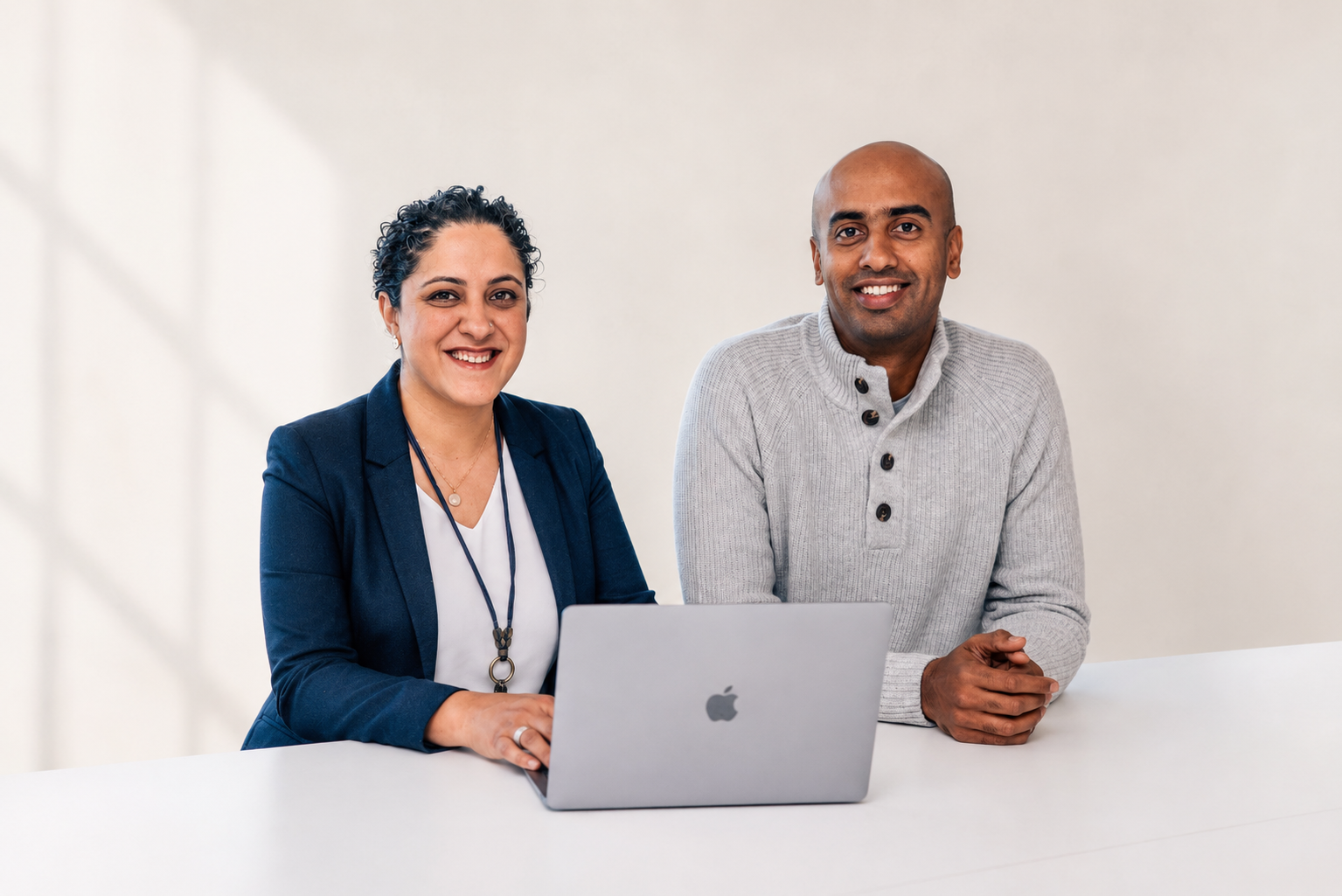 Avani and Amish from SME Digital Team sit at a table with a laptop, smiling, ready to discuss SEO for Chatswood businesses.